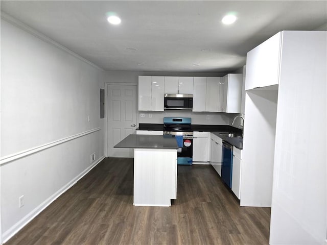 kitchen with appliances with stainless steel finishes, sink, white cabinets, dark hardwood / wood-style flooring, and a center island