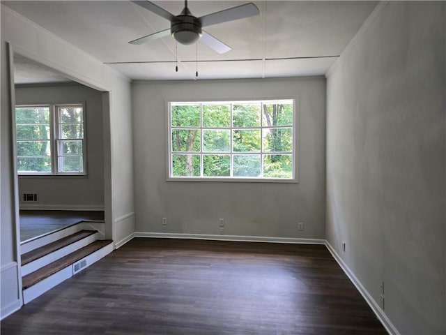 empty room with ceiling fan, dark hardwood / wood-style flooring, and a wealth of natural light