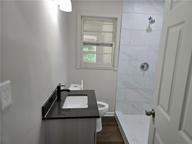 bathroom with vanity, toilet, hardwood / wood-style floors, and a tile shower