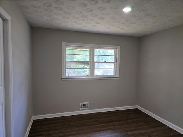 unfurnished room featuring dark hardwood / wood-style floors and a textured ceiling