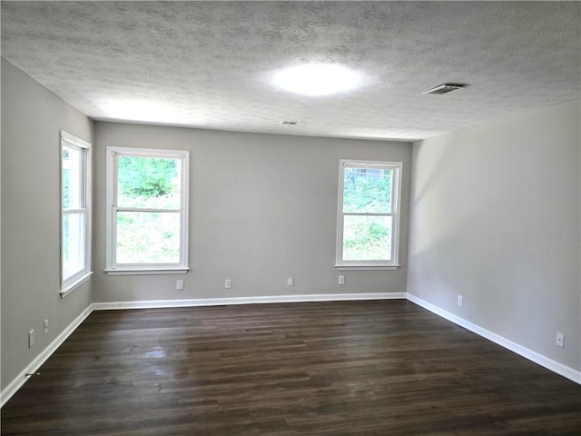 spare room featuring dark wood-type flooring and a textured ceiling