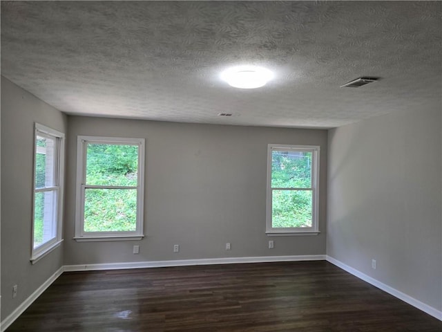 unfurnished room featuring dark wood-type flooring and a textured ceiling