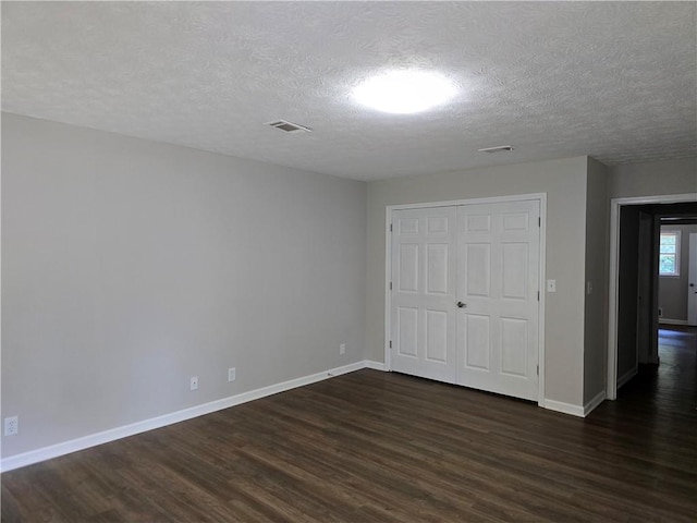 unfurnished bedroom featuring a closet, dark hardwood / wood-style floors, and a textured ceiling