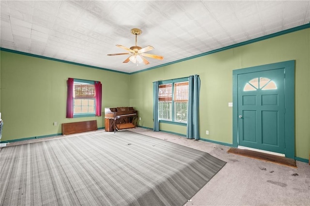 carpeted entryway featuring ceiling fan and crown molding