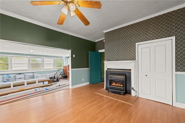 unfurnished living room with ceiling fan, light hardwood / wood-style floors, ornamental molding, and a textured ceiling