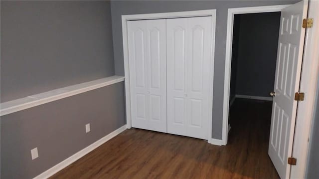 unfurnished bedroom with a closet and dark hardwood / wood-style flooring