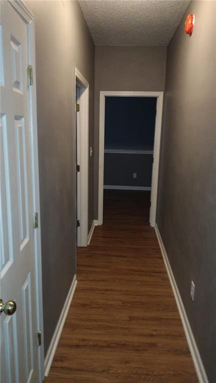 hallway featuring dark wood-type flooring and a textured ceiling