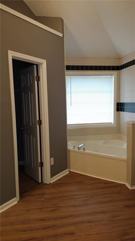 bathroom featuring lofted ceiling, a tub, and hardwood / wood-style flooring