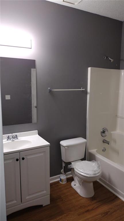 full bathroom with toilet, vanity, shower / bathing tub combination, wood-type flooring, and a textured ceiling