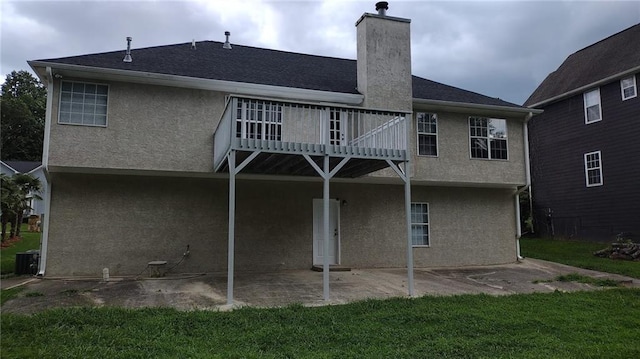 back of house featuring central air condition unit, a balcony, and a yard