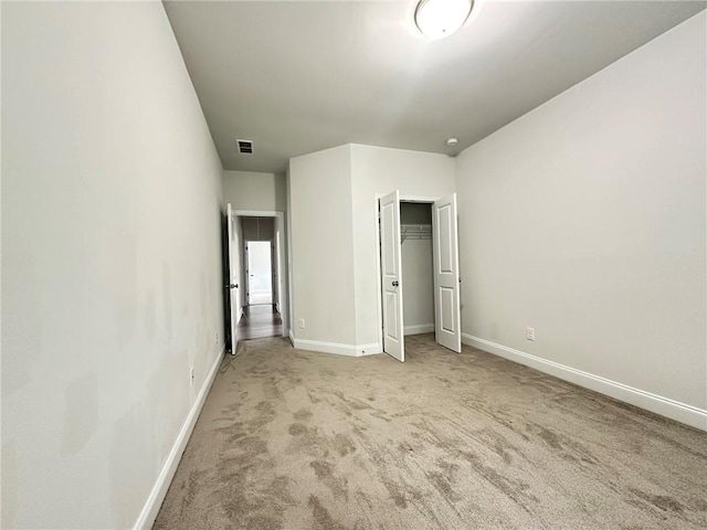 unfurnished bedroom with a closet and light colored carpet