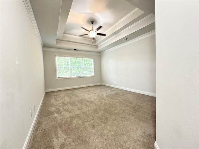 spare room with ceiling fan, a tray ceiling, carpet, and ornamental molding