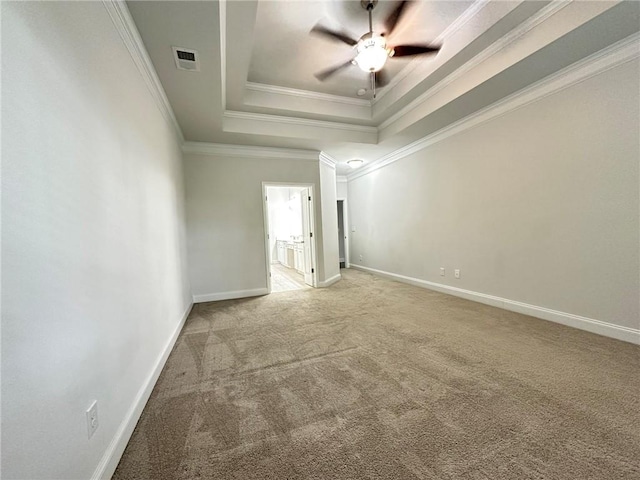 carpeted empty room featuring ceiling fan, a raised ceiling, and crown molding