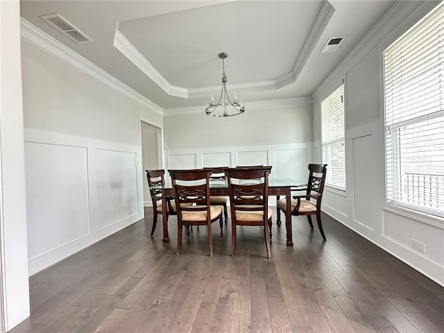 dining area with crown molding, dark hardwood / wood-style floors, a chandelier, and a tray ceiling