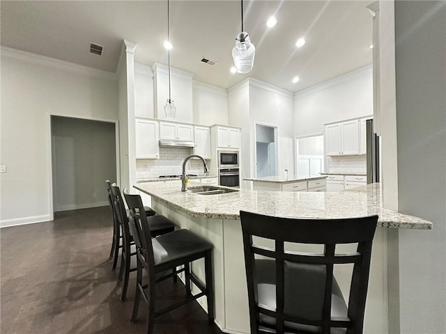 kitchen with stainless steel appliances, white cabinets, ornamental molding, a breakfast bar, and pendant lighting