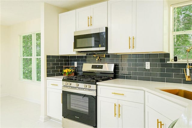 kitchen with white cabinets, backsplash, light countertops, and stainless steel appliances