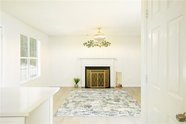 living room with baseboards, light wood-style floors, and a fireplace with flush hearth
