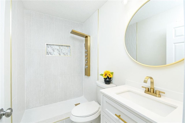 full bathroom with a tile shower, vanity, and toilet