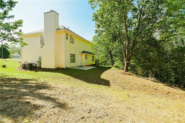 back of property featuring a chimney and a lawn