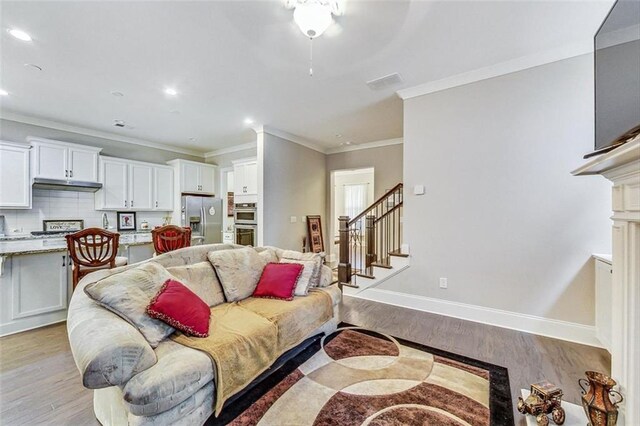 living room featuring ceiling fan, light wood-type flooring, and ornamental molding