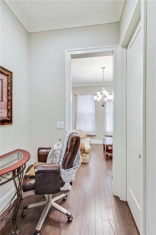 home office featuring wood-type flooring, crown molding, and a chandelier