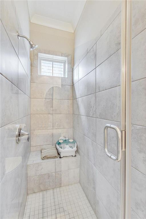 bathroom with crown molding and a shower with door