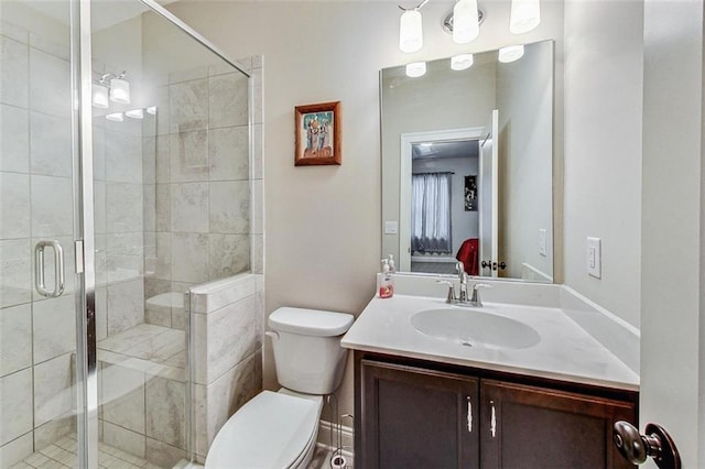 bathroom featuring vanity, toilet, and a shower with door