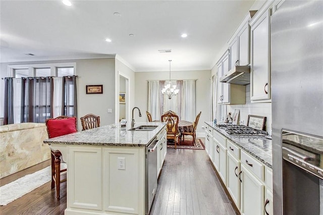 kitchen featuring an island with sink, sink, decorative light fixtures, appliances with stainless steel finishes, and dark hardwood / wood-style floors