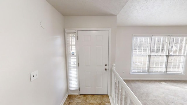 carpeted entrance foyer with a healthy amount of sunlight and a textured ceiling