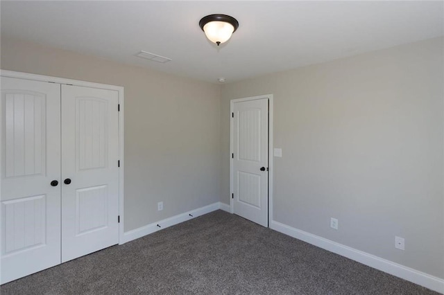 unfurnished bedroom featuring dark colored carpet and a closet