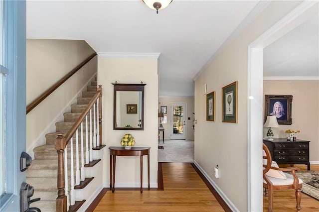 entryway featuring ornamental molding, baseboards, light wood finished floors, and stairs