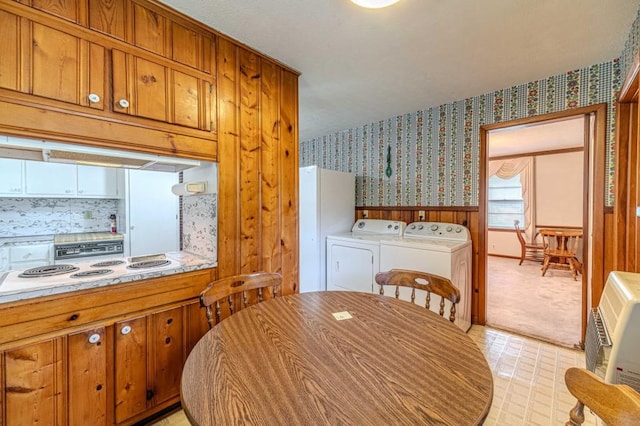 dining area featuring wallpapered walls, wainscoting, heating unit, light floors, and washing machine and dryer