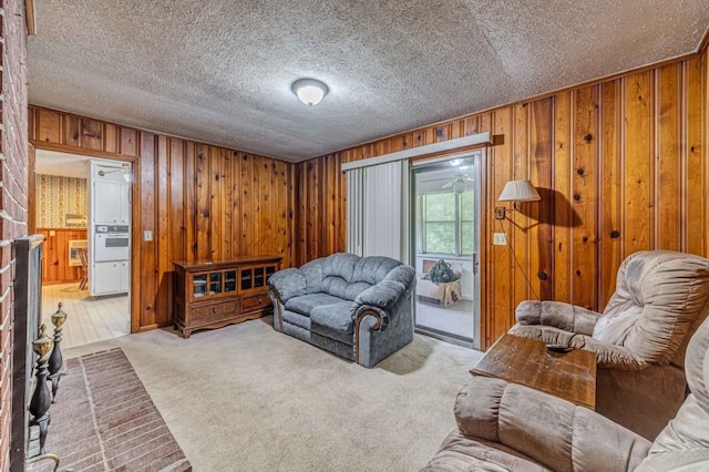 living room with a textured ceiling, wooden walls, a fireplace, and light colored carpet