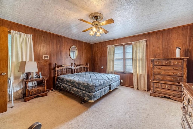 bedroom featuring light colored carpet, wood walls, a textured ceiling, and ceiling fan