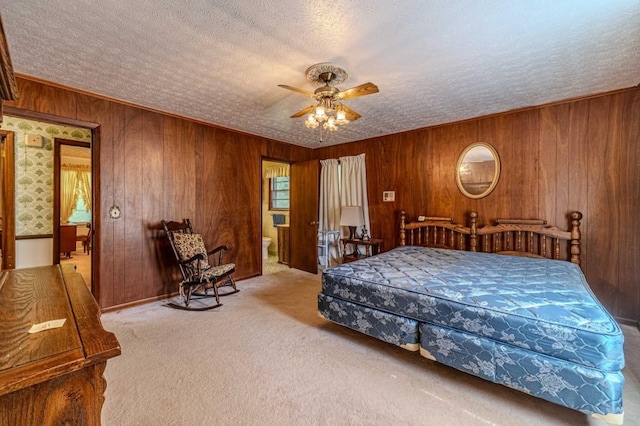 carpeted bedroom featuring crown molding, a ceiling fan, wood walls, connected bathroom, and a textured ceiling