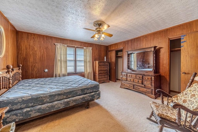 bedroom with a textured ceiling, ornamental molding, wood walls, and carpet