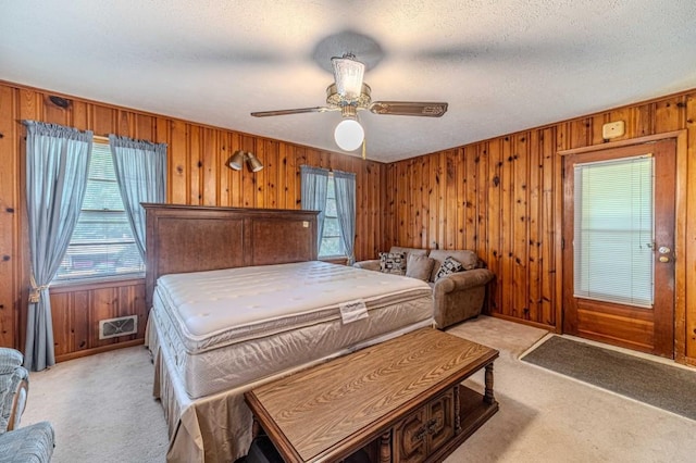 bedroom with light carpet, a textured ceiling, visible vents, and wooden walls