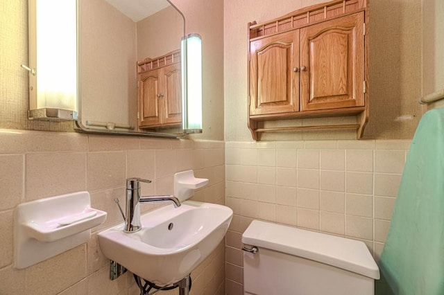 bathroom with wainscoting, a sink, tile walls, and toilet