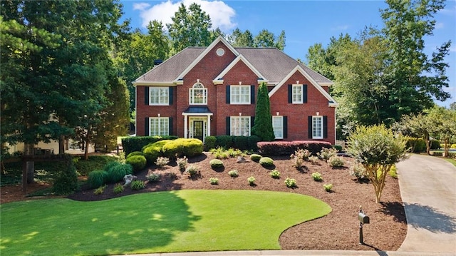 colonial-style house with brick siding and a front lawn