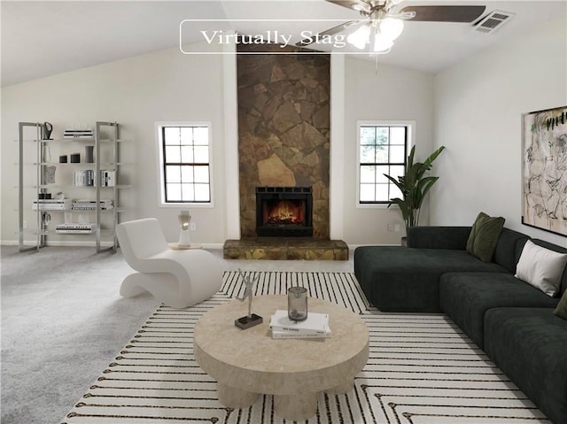 living room with carpet floors, vaulted ceiling, ceiling fan, and a stone fireplace