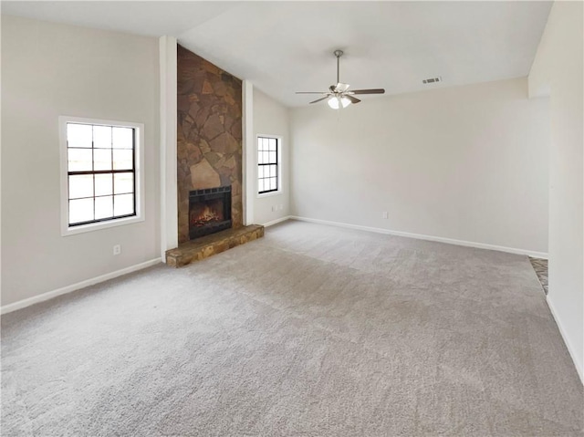 unfurnished living room with a stone fireplace, ceiling fan, carpet floors, and lofted ceiling