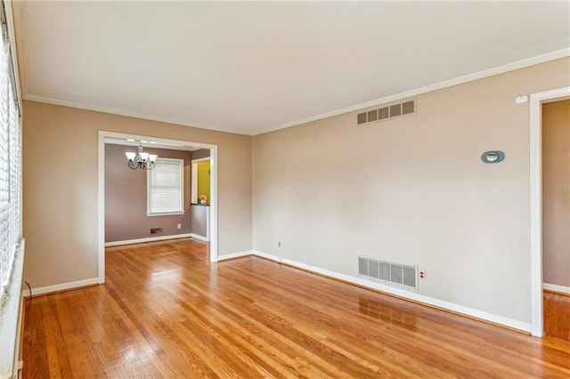 empty room with crown molding, hardwood / wood-style flooring, and a chandelier