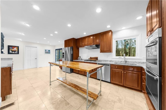 kitchen featuring light stone counters, stainless steel appliances, sink, and light tile patterned floors