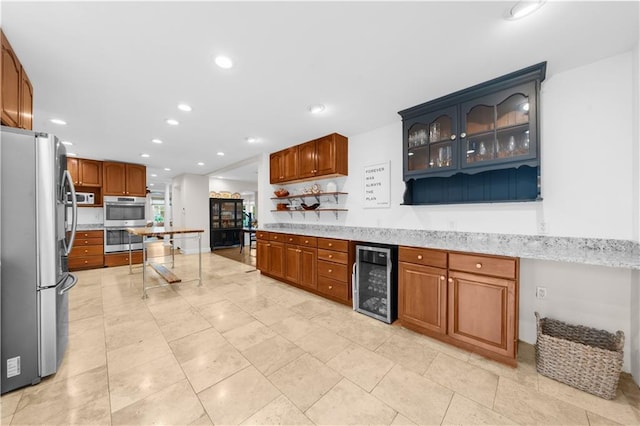 kitchen with light stone counters, stainless steel appliances, and beverage cooler