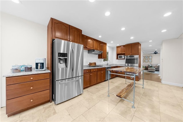 kitchen featuring light stone counters, sink, stainless steel appliances, and ceiling fan