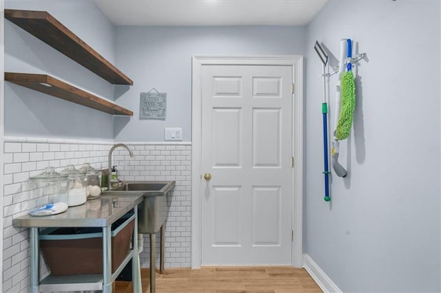 laundry area with tile walls, sink, and light hardwood / wood-style flooring