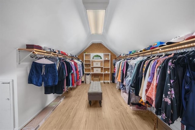 spacious closet with light hardwood / wood-style flooring and vaulted ceiling