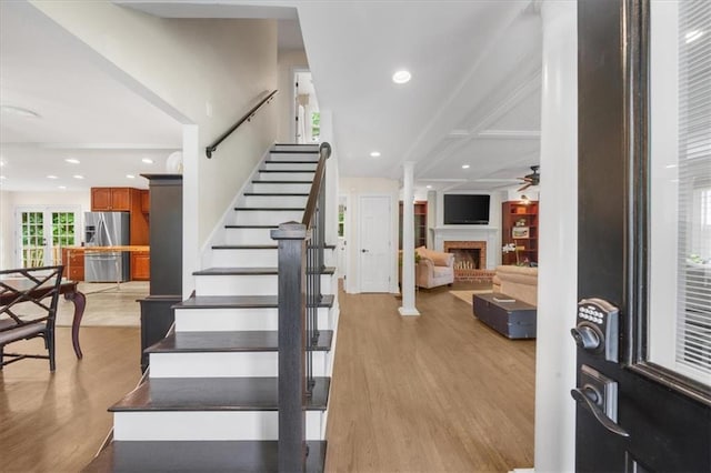 staircase featuring hardwood / wood-style flooring, ceiling fan, and decorative columns