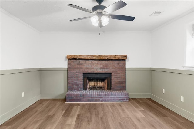 unfurnished living room with light hardwood / wood-style flooring, a fireplace, ornamental molding, and ceiling fan