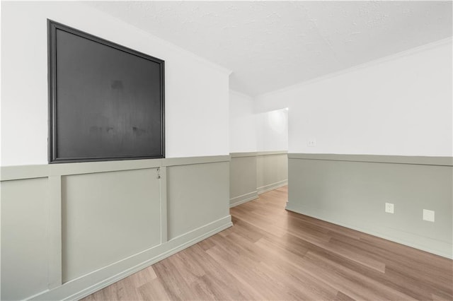 empty room with crown molding, a textured ceiling, and light hardwood / wood-style flooring